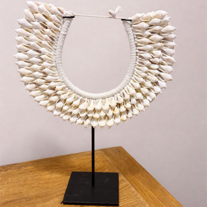 Εντυπωσιακό χειροποίητο διακοσμητικό κολιέ από φυσικά κοχύλια, τοποθετημένο σε κομψή μαύρη μεταλλική βάση. Ένα statement κομμάτι εμπνευσμένο από την εξωτική αισθητική και τη φυσική ομορφιά της θάλασσας, ιδανικό για να προσθέσει χαρακτήρα και μοναδικότητα σε κάθε χώρο. Η πλούσια υφή των κοχυλιών και η προσεγμένη δεσίματα δημιουργούν ένα αντικείμενο υψηλής αισθητικής που ταιριάζει άψογα σε boho, ethnic, coastal ή μοντέρνα διακόσμηση. Τοποθετήστε το σε κονσόλα, μπουφέ, βιβλιοθήκη ή τραπεζάκι σαλονιού και μεταμορφώστε άμεσα τον χώρο. Ένα ξεχωριστό διακοσμητικό αντικείμενο που τραβάει τα βλέμματα και προσθέτει αίσθηση ταξιδιού και πολυτέλειας στον χώρο σας.